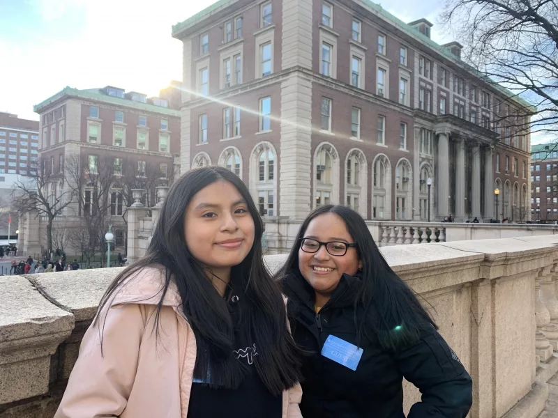 Two young women visiting Columbia University posing in front of building