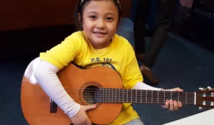 Girl plays guitar in the SCS Cornerstone Program's Music Room