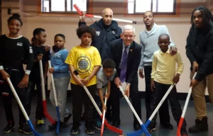 Children with hockey sticks and NYC Council Majority Speaker Jimmy Van Bramer during a visit