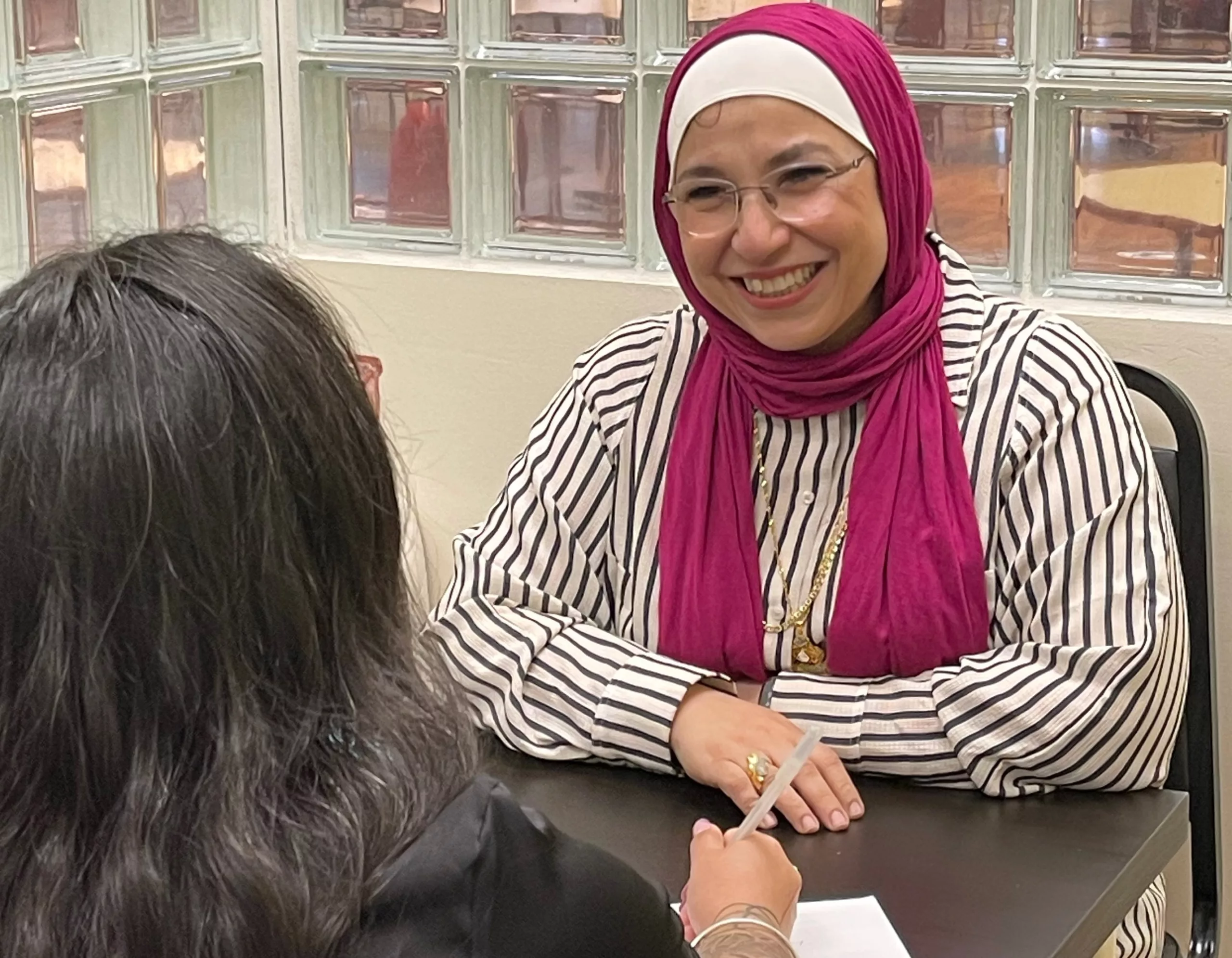 A woman smiling while helping another woman with legal support